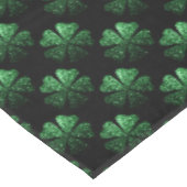 Dunkelgrünes funkelnd Kleeblatt auf schwarz Tischdecke (Schrägansicht)