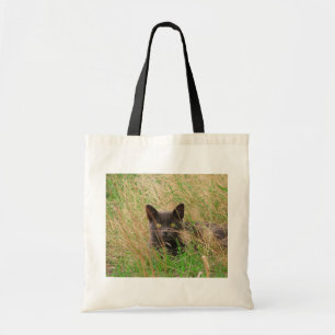 Dunkle graue Katze, die aus dem Gras herauspinkelt Tragetasche