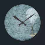 Dusk Blue Hot Air Balloon Steampunk Handwriting Runde Wanduhr<br><div class="desc">Matches other Steampunk hot air balloon design items such as cards and wrapping paper. Great for aviators and other air travel fans. This design features a Victorian Steampunk Hot Air Balloon gently flying in front of a scrapbook background page filled with handwriting washed with shades of soft, dusk blue. This...</div>