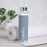 Dusty Blue Personalisiert Wedding Bridesmaid Trinkflasche<br><div class="desc">Gönnen Sie Ihrer Hochzeitsjury oder Ihrer Trauzeugin diese trendige, vakuumisolierte Wasserflasche, die ihren Namen in weißem, stilisiertem Schrift auf einem staubblauen Hintergrund hat, der zu Ihrem Hochzeitsfarbenschema passt. Stellen Sie die Flasche nach Belieben durch Bearbeiten und Ersetzen des Namens durch Ihren eigenen Namen ein. Wählen Sie Ihre Wasserflasche. Erhältlich in...</div>