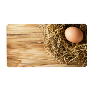 Ei im Heu-Nest auf hölzernem Tabellen-Hintergrund