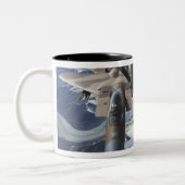 Ein Adlerflugzeug des Typs F-15C sitzt hinter eine Zweifarbige Tasse (Links)