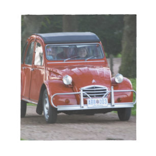 Ein alter roter Citroen 2CV Wagen mit einer lächel Notizblock