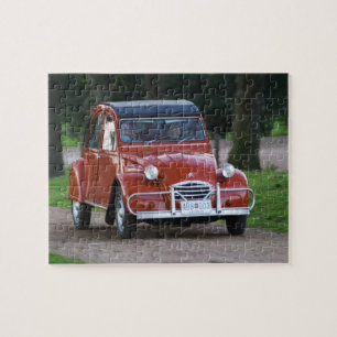 Ein alter roter Citroen 2CV Wagen mit einer lächel Puzzle