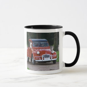 Ein alter roter Citroen 2CV Wagen mit einer lächel Tasse