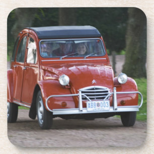 Ein altes, rotes Citroen 2CV Auto mit einer läche Getränkeuntersetzer
