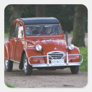 Ein altes, rotes Citroen 2CV Auto mit einer läche Quadratischer Aufkleber