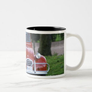 Ein altes, rotes Citroen 2CV Auto mit einer läche Zweifarbige Tasse