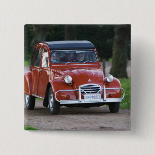 Ein altes, rotes Citroen 2CV Auto mit einer lächel Button
