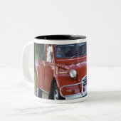 Ein altes, rotes Citroen 2CV Auto mit einer lächel Zweifarbige Tasse (Vorderseite Links)