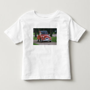 Ein altes rotes Citroen 2CV Auto mit einer lächeln Kleinkind T-shirt