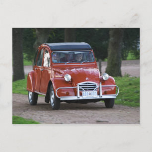 Ein altes rotes Citroen 2CV Auto mit einer lächeln Postkarte