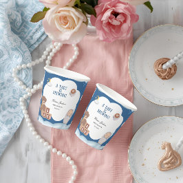 Ein Baby brütet eine Kaffeemaschine. Pappbecher