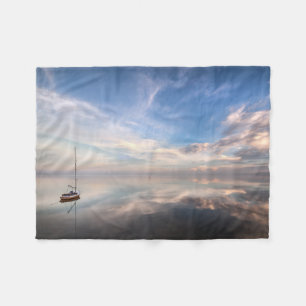 Ein einziges Segelboot auf dem ruhigen Wasser von Fleecedecke