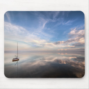 Ein einziges Segelboot auf dem ruhigen Wasser von Mousepad