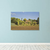 Ein gezüchtetes Feld vor Strohdächern Leinwanddruck (Insitu (Holzboden))