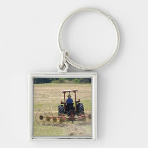 Ein junger Junge fährt einen Traktor zur Ernte Schlüsselanhänger