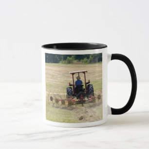 Ein junger Junge fährt einen Traktor zur Ernte Tasse