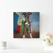 Ein kleiner, vor einigen Strandhütten Stehender Ba Quadratische Wanduhr (Zuhause)