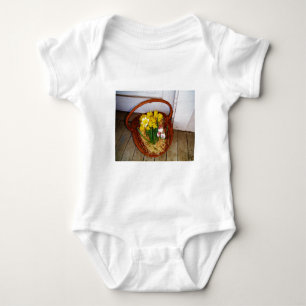 Ein Korb voller gelber Narzissen und florales Oste Baby Strampler