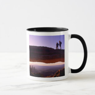 Ein paar beobachten Sonnenaufgang vom Mesa Arch in Tasse