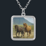 Ein Paar brauner isländischer Ponys Versilberte Kette<br><div class="desc">Ein absolut niedliches und bezauberndes Foto,  das zwei eiskelandische Ponys auf einer Schotterstraße festnimmt. Einer ist eine Bucht,  der andere ist kastanienfarben. Ihre prächtigen Mähne wehen im Wind. Eine wunderschöne Berglandschaft kann im Hintergrund gesehen werden und verleiht diesem Bild ein Gefühl des Staunens. Für Pferdefreunde und Reiter jeden Alters.</div>