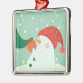 Ein Schneemann, der eine Verzierung auf einem Baum Silbernes Ornament (Links)
