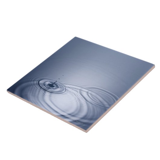 Ein Singletröpfchen des Wassers fallend in eine Fliese (Seite)