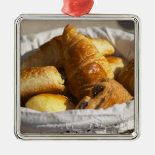 Ein Weiden-Frühstückskorbe mit Croissants und Silbernes Ornament