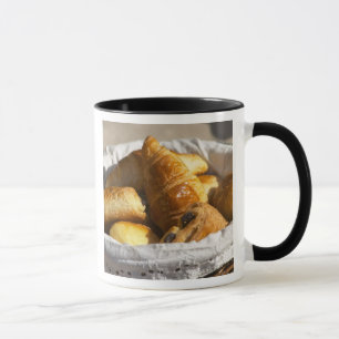 Ein Weiden-Frühstückskorbe mit Croissants und Tasse