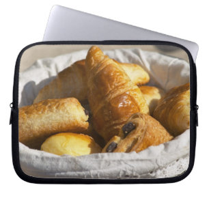 Ein Weidenkörbchen mit Croissants und Laptopschutzhülle