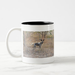 Ein wilder (gemalter) Hund steht im Bush, Sambia. Zweifarbige Tasse