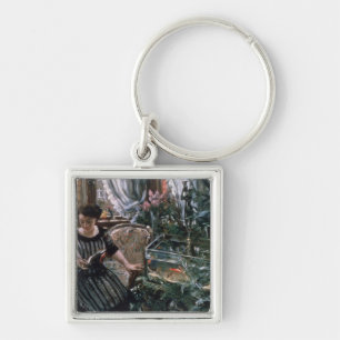 Eine Frau, die nahe einem Goldfisch-Behälter lies Schlüsselanhänger