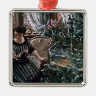 Eine Frau, die nahe einem Goldfisch-Behälter lies Silbernes Ornament