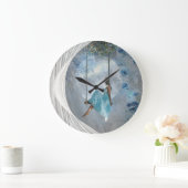 Eine Frau in blauem Kleid auf einer Schaukel Große Wanduhr (Zuhause)