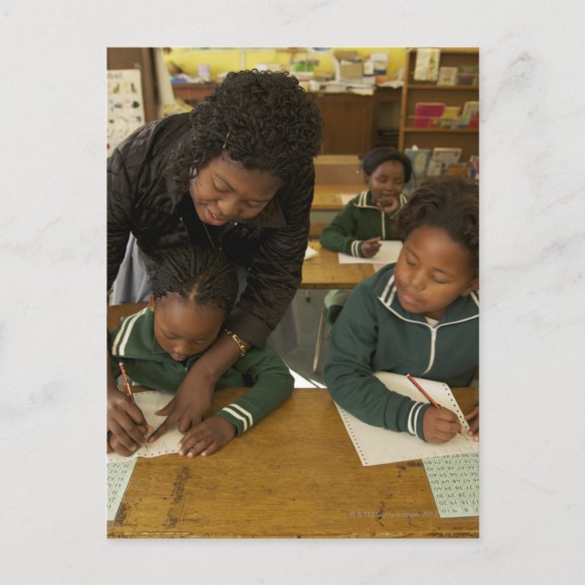 Eine Lehrerin unterstützt kleine Schulkinder in ih Postkarte (Vorderseite)