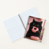 Eine schwarze Katze hält rosa Donuts in ihren Pfot Notizblock (Innenseite)