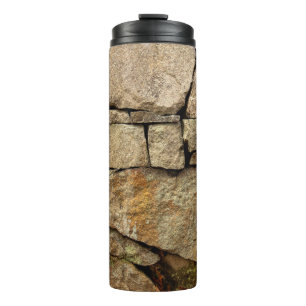 Eine Steinmauer aus Kopfsteinpflaster Hintergrundt Thermosbecher