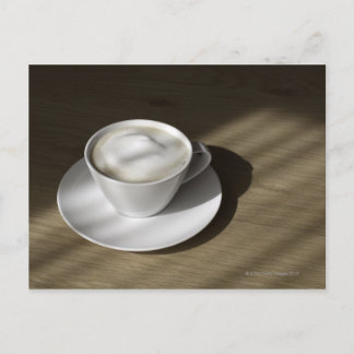 Eine Tasse Cappuccino Kaffee liegt auf einer Eiche Postkarte