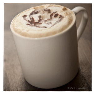 Eine Tasse Cappuccinokaffee überstieg mit Fliese
