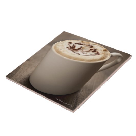 Eine Tasse Cappuccinokaffee überstieg mit Fliese (Seite)