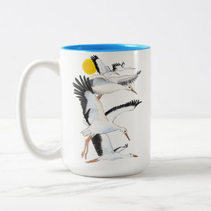Eine Uhr weißer Storchen, die über die Sonnenstrah Zweifarbige Tasse