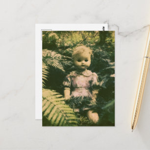 Eine verlassene gruselige Puppe im Wald Postkarte