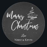 Elegant Chalkboard Script Merry Christmas Tree Runder Aufkleber<br><div class="desc">Elegantes Chalkboard Script Frohe Weihnachtsbaum Classic Round Sticker. Passen Sie es an,  indem Sie die Namen ändern. Das Design hat frohe Weihnachten geschrieben in hübschem Schriftart auf einem Kreideboden zusammen mit den Namen des Paares. Für weitere Anpassungen wenden Sie sich bitte an mich unter mypaperlove2021@gmail.com</div>