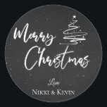 Elegant Chalkboard Script Merry Christmas Tree Runder Aufkleber<br><div class="desc">Elegantes Chalkboard Script Frohe Weihnachtsbaum Classic Round Sticker. Passen Sie es an,  indem Sie die Namen ändern. Das Design hat frohe Weihnachten geschrieben in hübschem Schriftart auf einem Kreideboden zusammen mit den Namen des Paares. Für weitere Anpassungen wenden Sie sich bitte an mich unter mypaperlove2021@gmail.com</div>