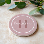 Elegant Dusty Rose Custom Monogram Initial Getränkeuntersetzer<br><div class="desc">Eleganter,  runder personalisierter Getränkedosen-Untersetzer-Design mit einem klassischen Serif-Monogramm,  das in staubiger Rose mit Ihrem Nachnamen in modernem,  weißem Kalligrafieschrift auf einem hellmauvem / staubigen Rose-Rosa Hintergrund initiiert wurde. Ein einfacher weißer Kreis umrahmt das Design. Das Farbschema kann so angepasst werden,  dass es sich perfekt mit Ihrer Wohngestaltung abstimmt.</div>