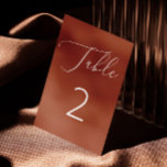 Elegante Terracotta Brick Minimalistische Hochzeit Tischnummer<br><div class="desc">Diese elegante Tischnummer-Karte mit einem verbrannten siennabischen Hintergrund, einem zarten, weißen Drehbuch und einer gepflegten Typografie für einen warmen, raffinierten Look. Die warme Terracotta-Ziegelfarbe verleiht Ihrem Dekor ein gemütliches, herbstliches Ambiente, während der weiche Rostton für Hochzeiten im Herbst, Bohthemden oder rustikale Veranstaltungen geeignet ist. Dieses Minimalistische und doch kühne Design...</div>