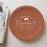 Elegantes Script Terracotta Cheers to the Graduate Pappteller<br><div class="desc">Elegante Abschluss-Papier-Teller mit einer Graduationskappe mit dem Satz "Cheers to the Graduate" in einem weißen Kalligrafieschrift auf Terrakotta-Hintergrund. Personalisieren Sie die modernen Abschluss-Papier-Teller mit dem Namen des Absolventen,  Schulname und Abschluss Jahr. Die einfachen Abschluss-Teller sind ideal für Ihr High School- oder Uni-Abschluss-Party.</div>