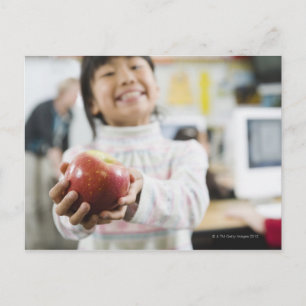 Elementarschülerin, die einen Apfel in der Hand hä Postkarte