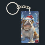 English Bulldog Winter Wonderland Christmas Joy Schlüsselanhänger<br><div class="desc">Dieses festliche Design spiegelt den fröhlichen Geist der Urlaubssaison wider und besticht durch ein hübsches Jungtier mit einer Weihnachtsmannmütze. Der Hund ist eingebettet in ein winterliches Wunderland, mit einem Schneemann, einem dekorierten Weihnachtsbaum und wunderschön verpackten Geschenken. Schneeflocken fallen sanft ab und geben der Szene eine magische Touch, während die lebhaften...</div>